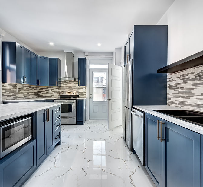 Contemporary kitchen renovation featuring navy cabinets, marble flooring, and stainless appliances — Home & Beyond Services kitchen remodeling in Stuart and Palm City, FL.