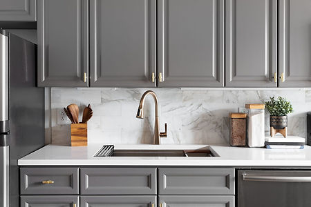 Modern kitchen with gray cabinets, marble backsplash, and a gold faucet