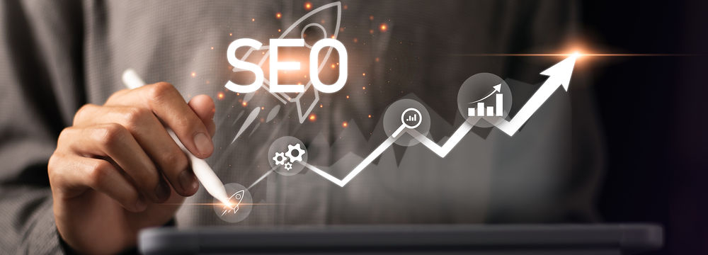 Hand holding pen drawing upward SEO growth graph with digital marketing icons.