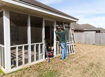 Technician repairing patio screen enclosure — Home & Beyond Services screen repair and replacement in Palm City, FL.