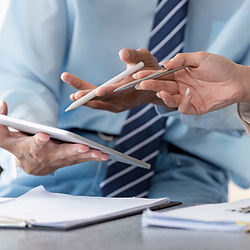 Two professionals in business attire discussing data on a tablet.