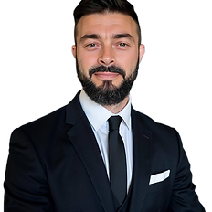 Professional man in a black suit and tie posing confidently against a white background.