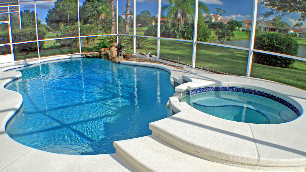 Screened pool with rock waterfall and spa overlooking golf course fairway in Port St. Lucie FL