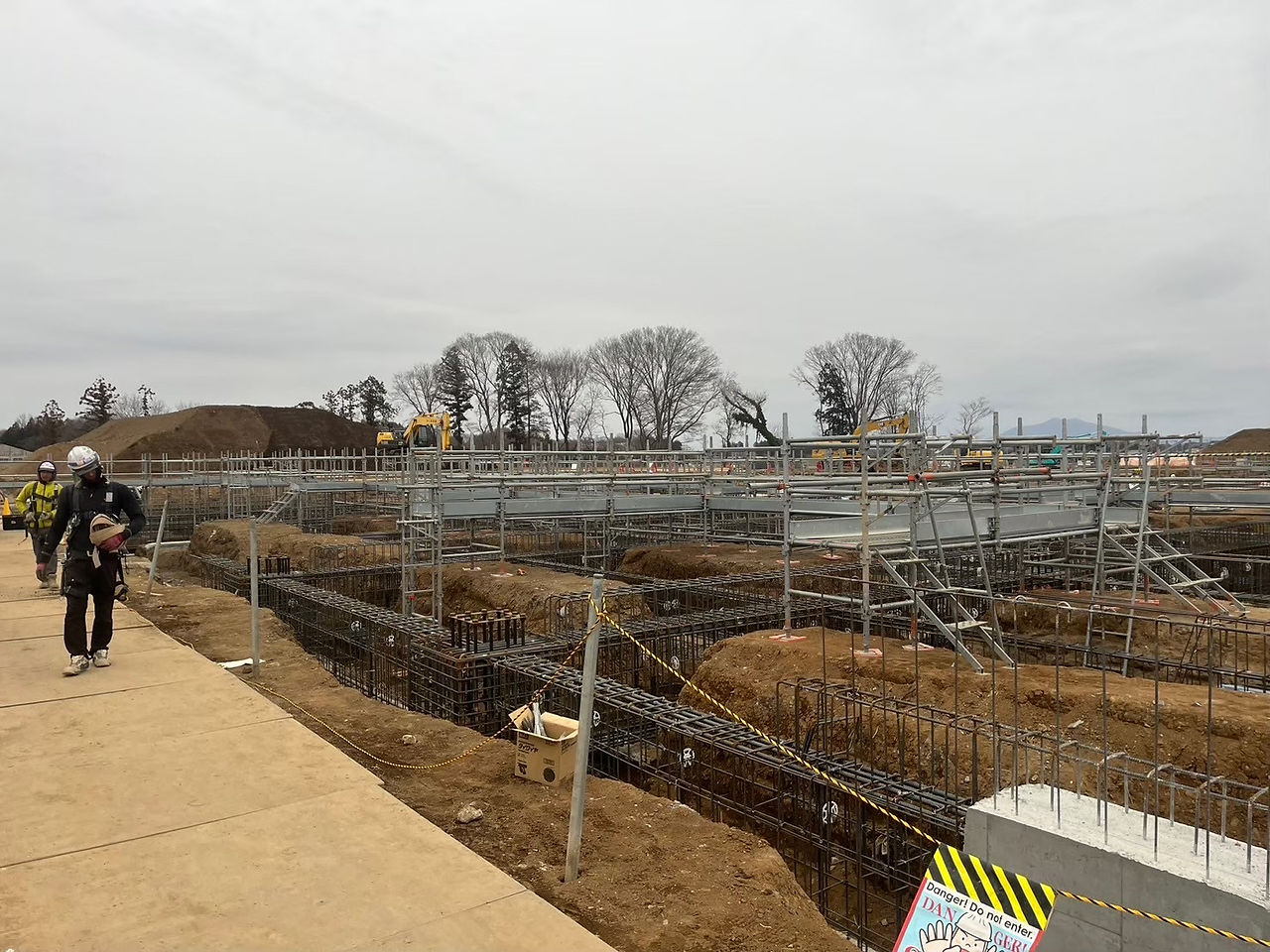 建設現場の風景、作業員と重機。アサヒプリテック株式会社　坂東工場建設工事、工事中の様子。