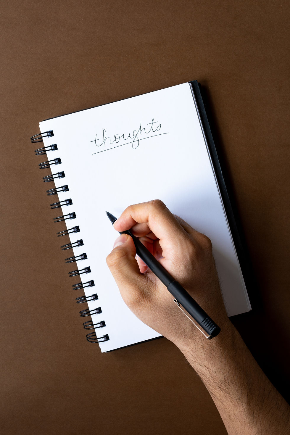 Hand holding pen writing on notepad
