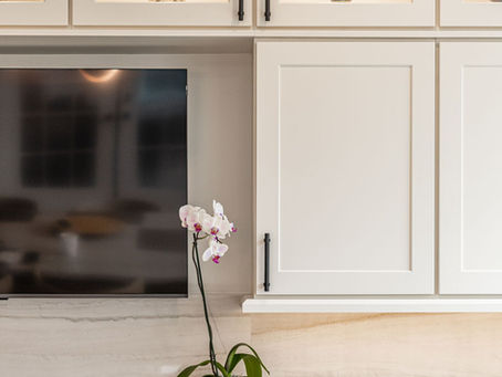 Kitchen cabinetry with a TV embedded. Cabinetry lights inside the glass cabinetry doors.