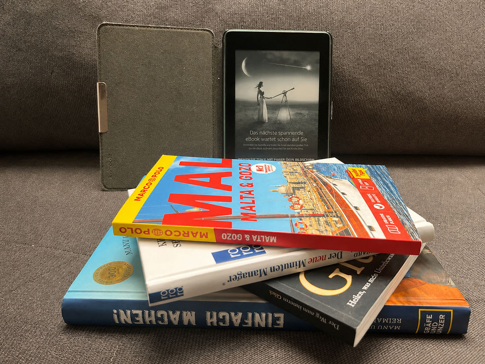 Bücherstapel und E-Reader auf einem Sofa