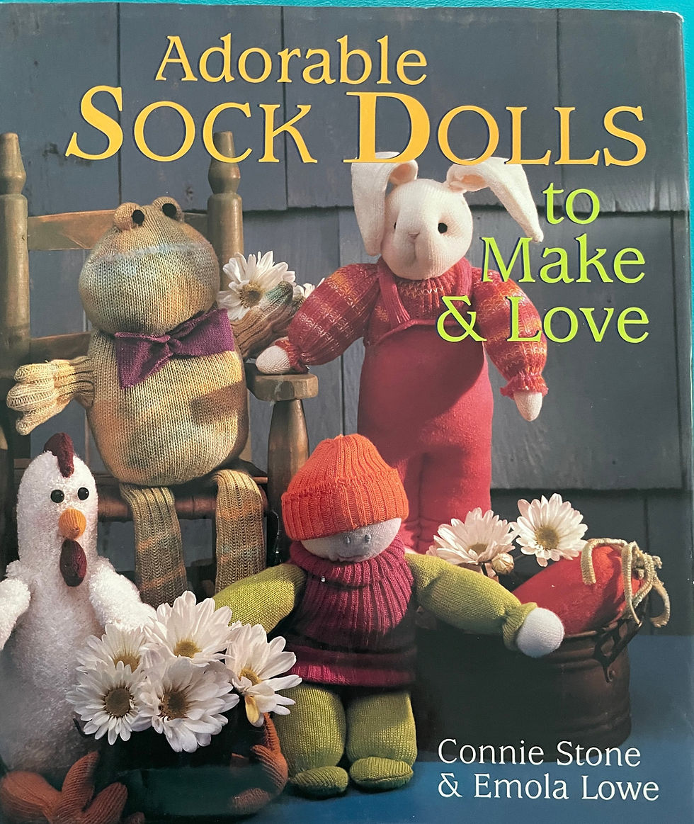 Book cover for 'Adorable Sock Dolls to Make & Love' by Connie Stone & Emola Lowe, featuring handmade sock dolls including a frog, rabbit, and child doll, posed with flowers against a rustic backdrop