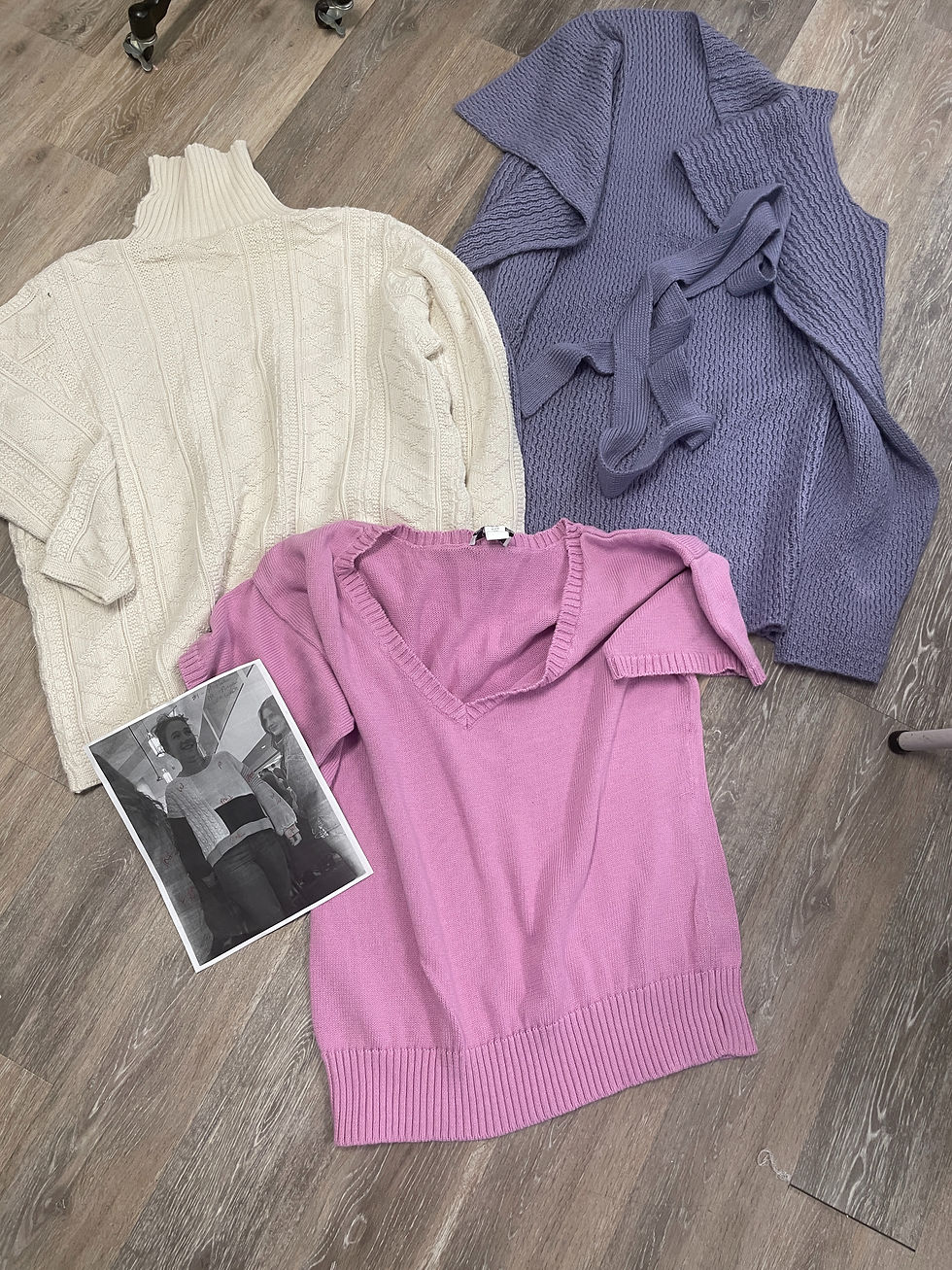 Thumbnail: Three original sweaters before Londa’s upcycle—purple, pink, and white—laid out flat, showing worn fabrics and patterns ready