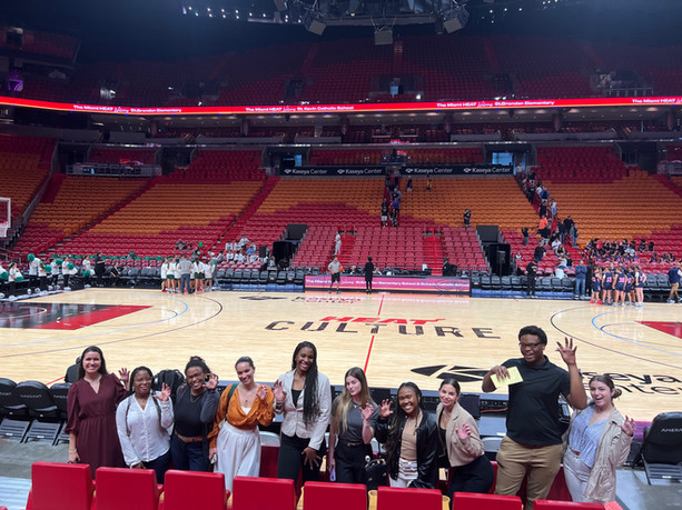 Students standing in front of the Miami HEAT basketball court in the Kaseya Center.