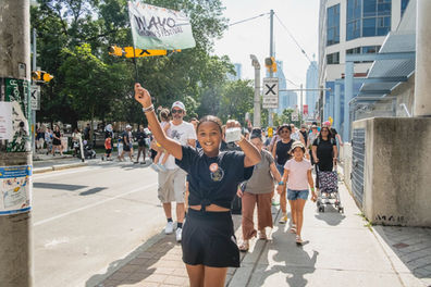 WAYO Children’s Festival team member carrying a festival flag while leading children and families to a 2026 performance in downtown Toronto.