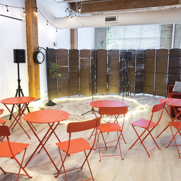Café-style event setup at The Jamii Hub with red tables and chairs facing a microphone and performance area.