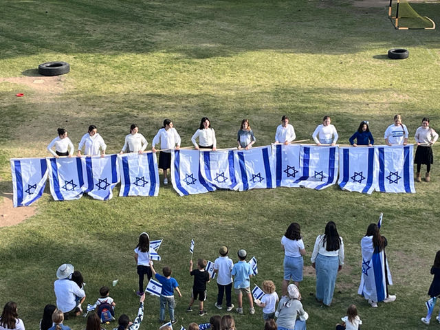 Students holding a long line of Israeli flags on the field
