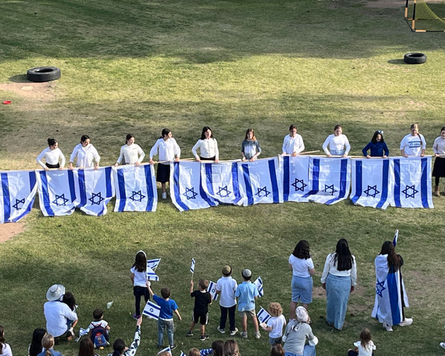 Students on the PHA field holding a long line of Israeli flags