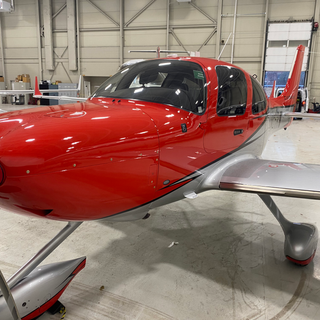 View from the red exterior nose of Cirrus SR22T biplane in a hanger