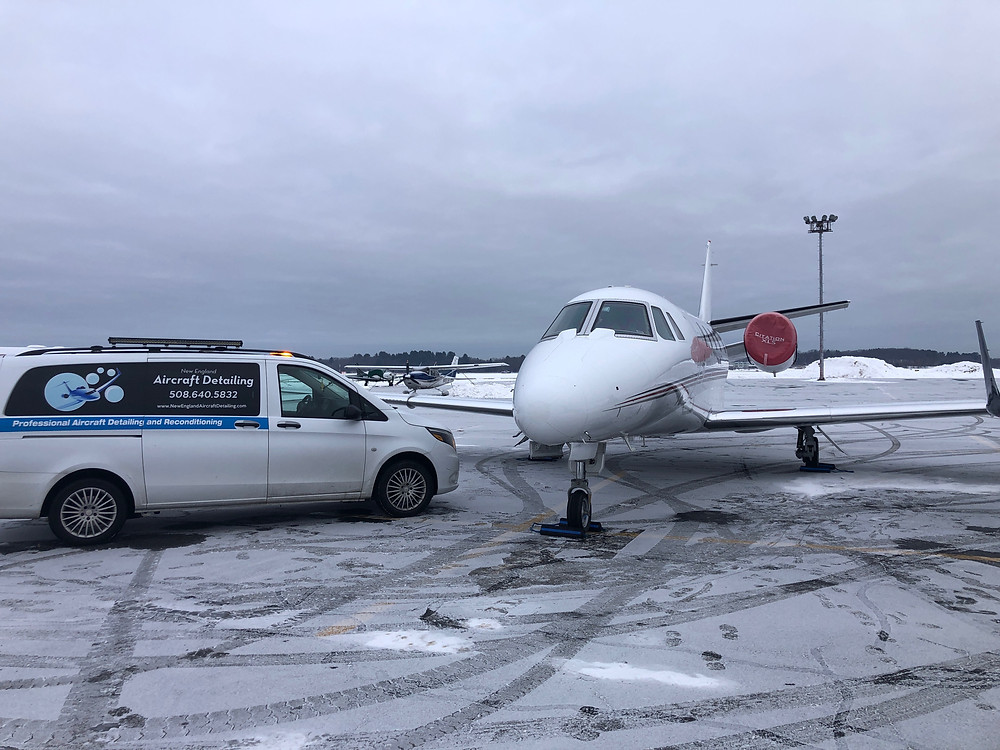 Exterior nose of Cessna Citation airplane on snowy runway next to a work van