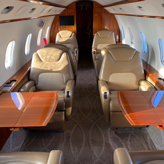 Interior of Challenger 300 aircraft with sun coming through windows on wooden tables and leather seats