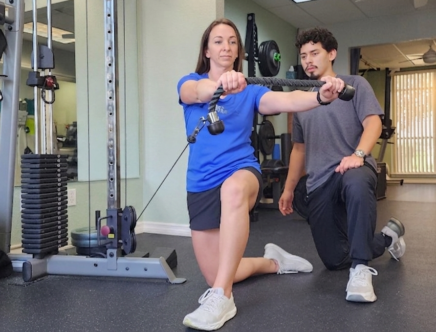 Exercise Physiologist coaching a client through a personalized strength exercise to improve movement quality.