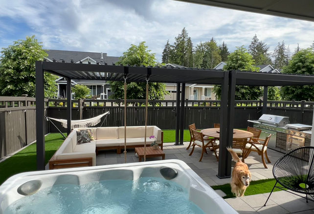Covered outdoor living space with paver patio, pergola, and hot tub in Ten Trails Community