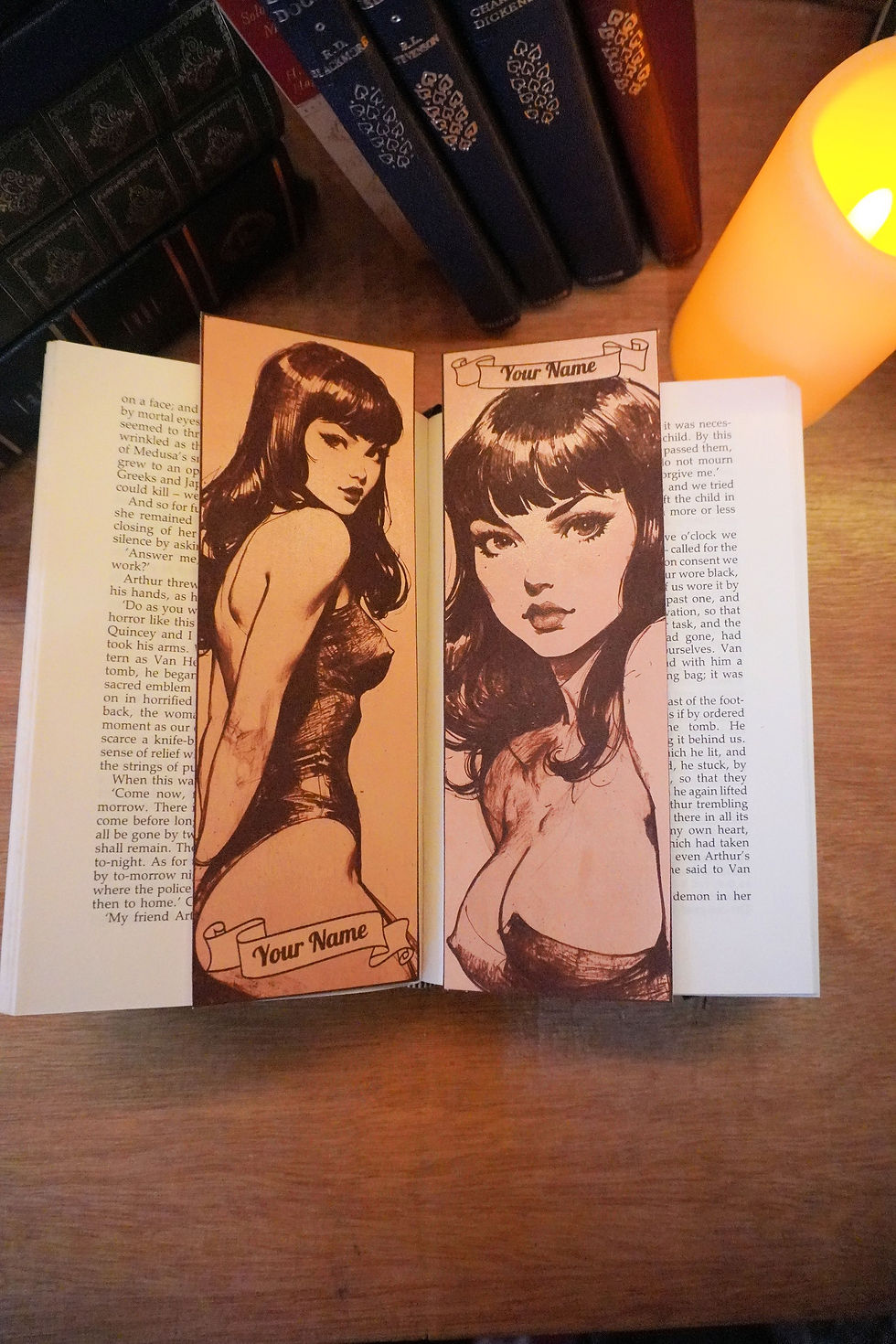 Leather bookmark lying on top of a book next to a candle with a 1950s Pin-Up Designs