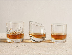 Three filled whiskey glasses in cut crystal, sculptural, and Japanese-inspired designs