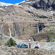 personas descansan durante un trekking en el cerro tronador en bariloche con cascadas de glaciar en el fondo