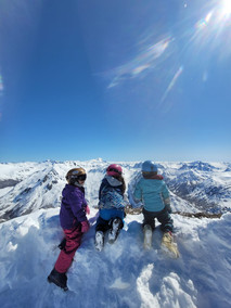 Tres niños miran las montañas nevadas en el Cero Catedral, en Bariloche