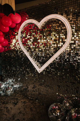 silver glitter wall with giant neon pink heart and hot pink balloons