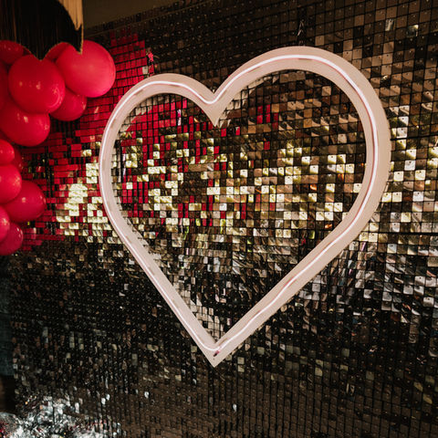 silver glitter wall with giant neon pink heart and hot pink balloons