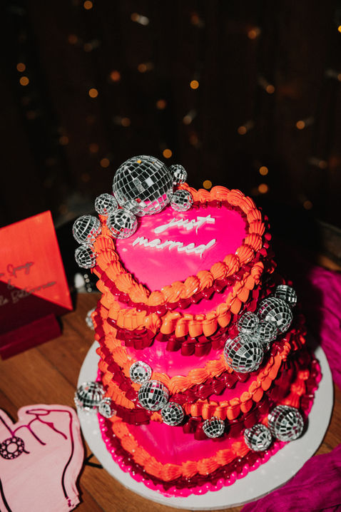 Hot pink and orange two tiered heart shaped wedding cake with disco balls on