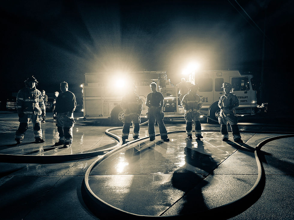 Six firefighters in uniform at night with fire truck