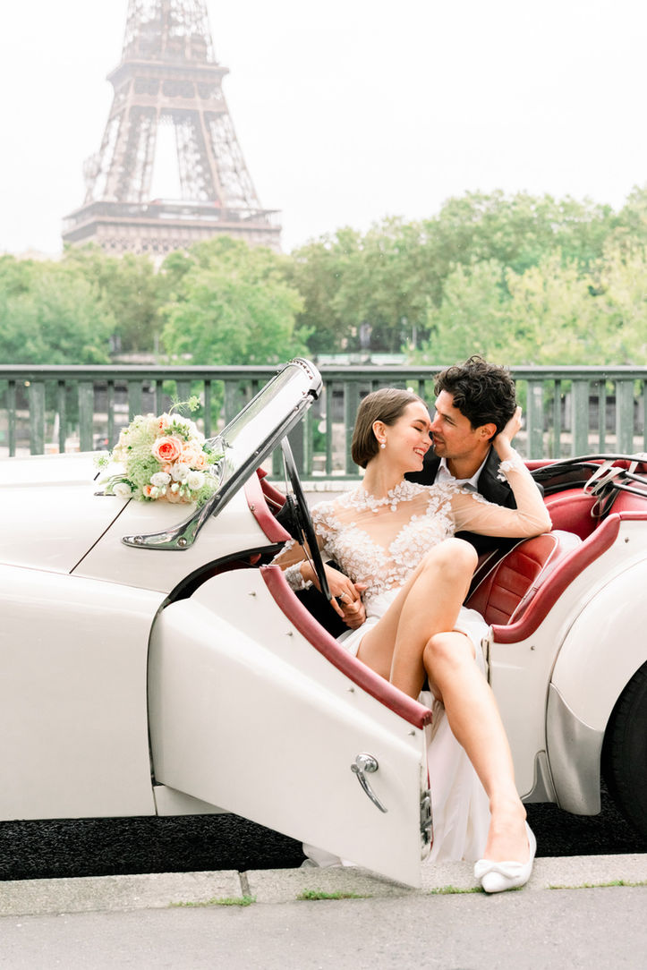 Bride and groom sharing a tender moment inside a classic vintage car during their wedding photoshoot in Paris.