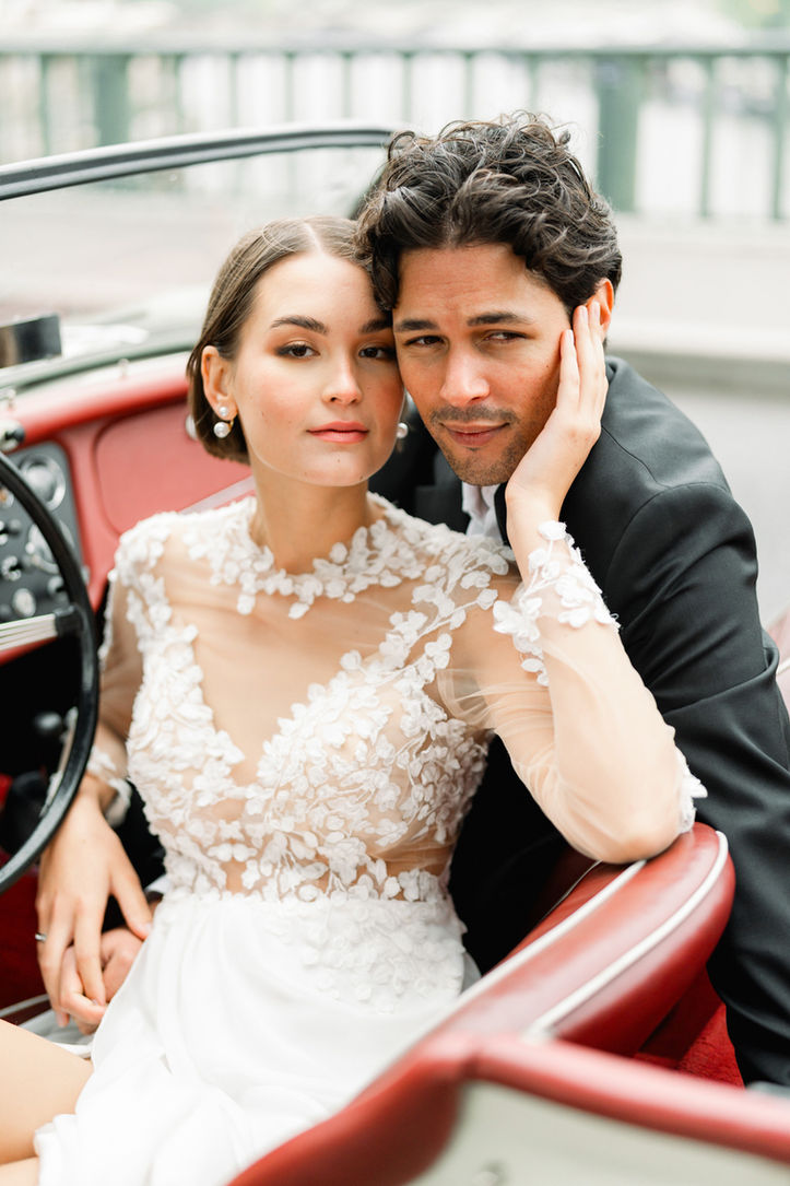 Bride and groom sharing a tender moment inside a classic vintage car during their wedding photoshoot in Paris.