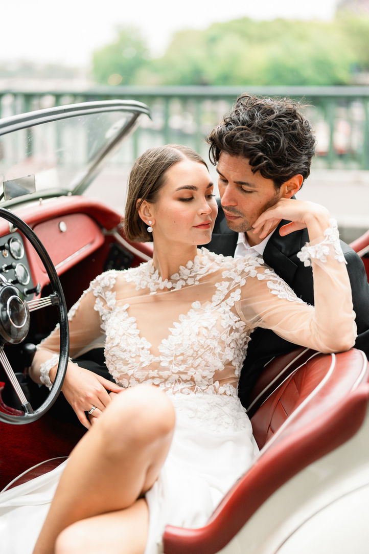 Bride and groom sharing a tender moment inside a classic vintage car during their wedding photoshoot in Paris.