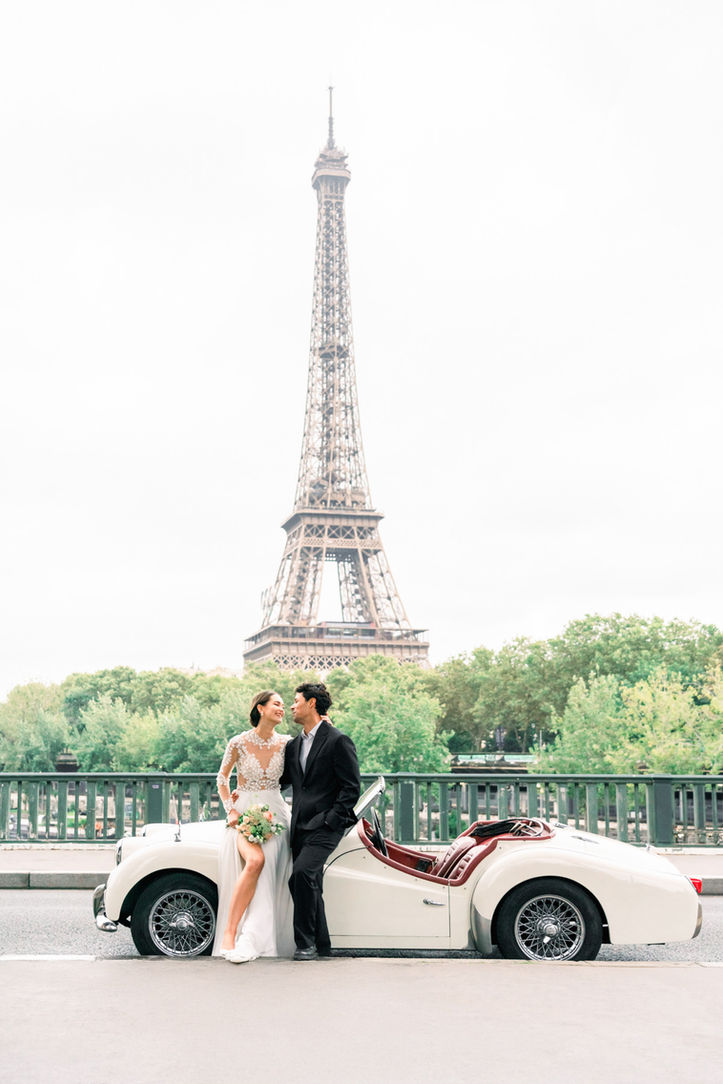 Couple posing beside a classic car during their Parisian wedding photoshoot.