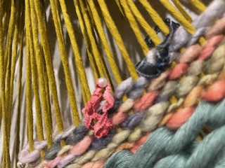 Yellow warp string on round hoop with beaded yarn weft