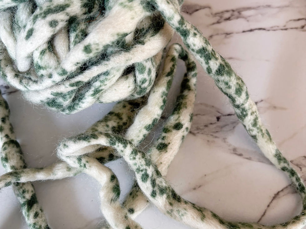 Thumbnail: A ball of natural felted wool with green splatters.