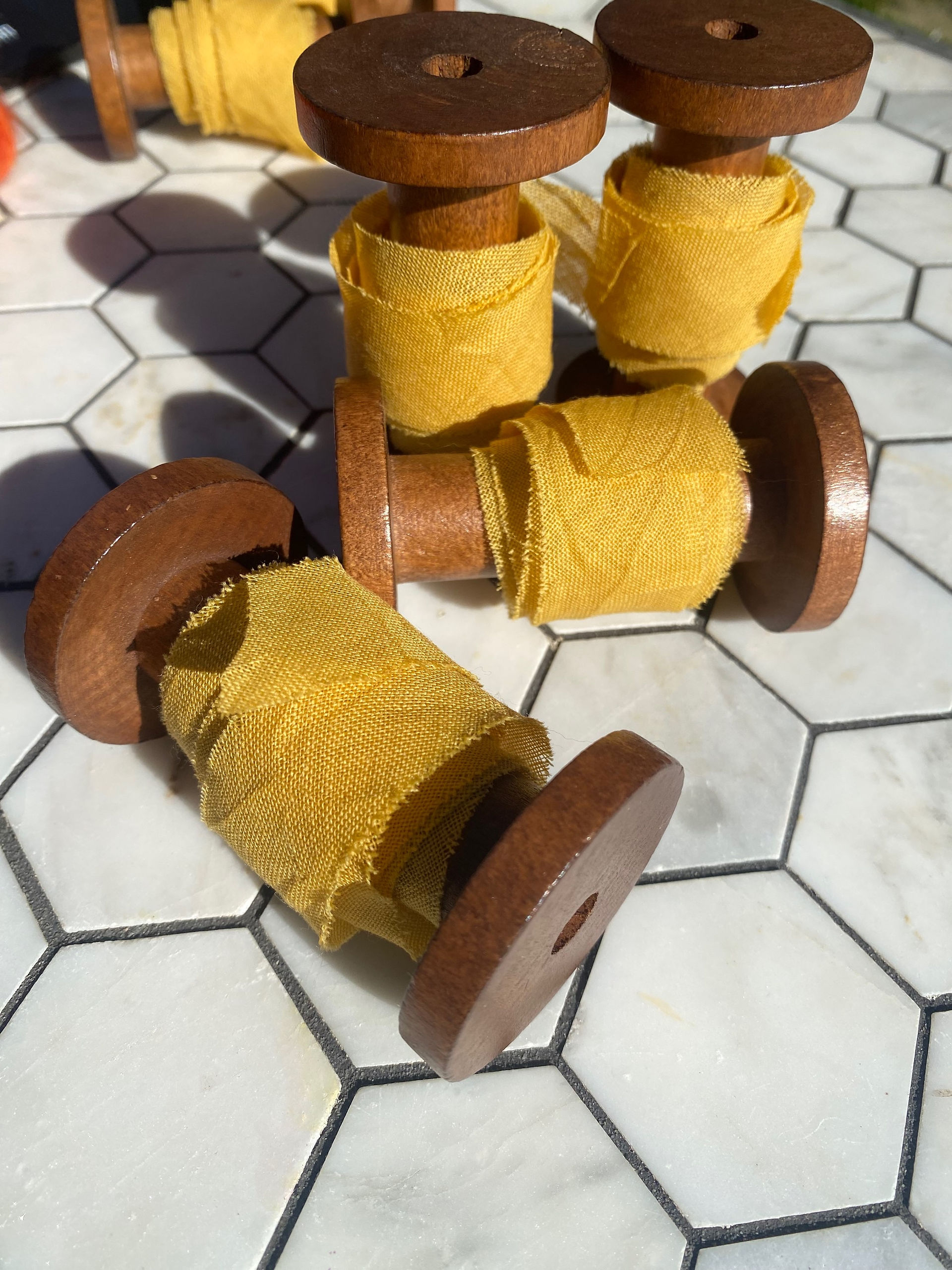 Yellow etamine ribbon on dark wooden bobbin