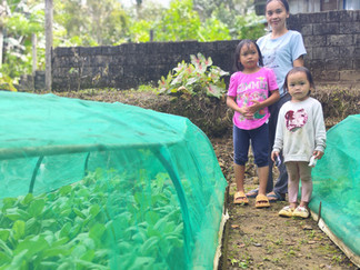 A rural farming beneficiary with her two children at their self-grown farm