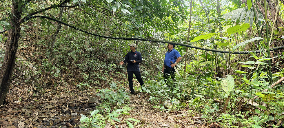 RuralKita field team member and villager examining an existing HDPE water pipeline along a rocky forest trail in Kampung Talukung, Kota Belud, Sabah.