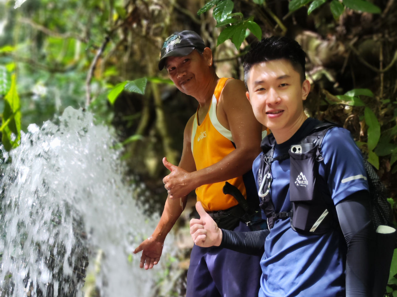 Sam and a rural villager celebrating the successful gravity water connection, with pipes now overflowing with water.