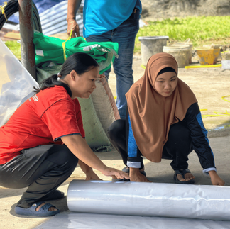 Farmers working together to sort and distribute farming materials among workshop participants.