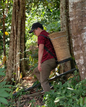 A volunteer carrying a traditional salabit basket while experiencing rural village life and harvesting local fruits and vegetables.