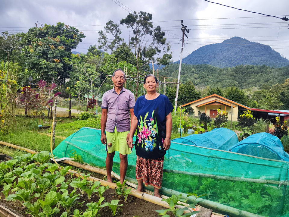 Local farming couple proudly standing in their vegetable farm,