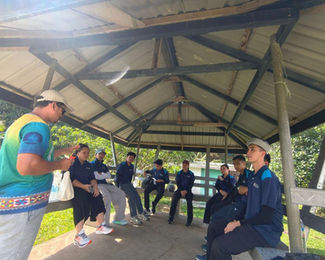 Efandi conducting a briefing session with volunteers, outlining the day's community farming and rural development activities.