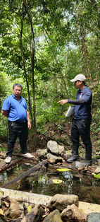 RuralKita member discussing technical site conditions during a forest field assessment in Sabah.