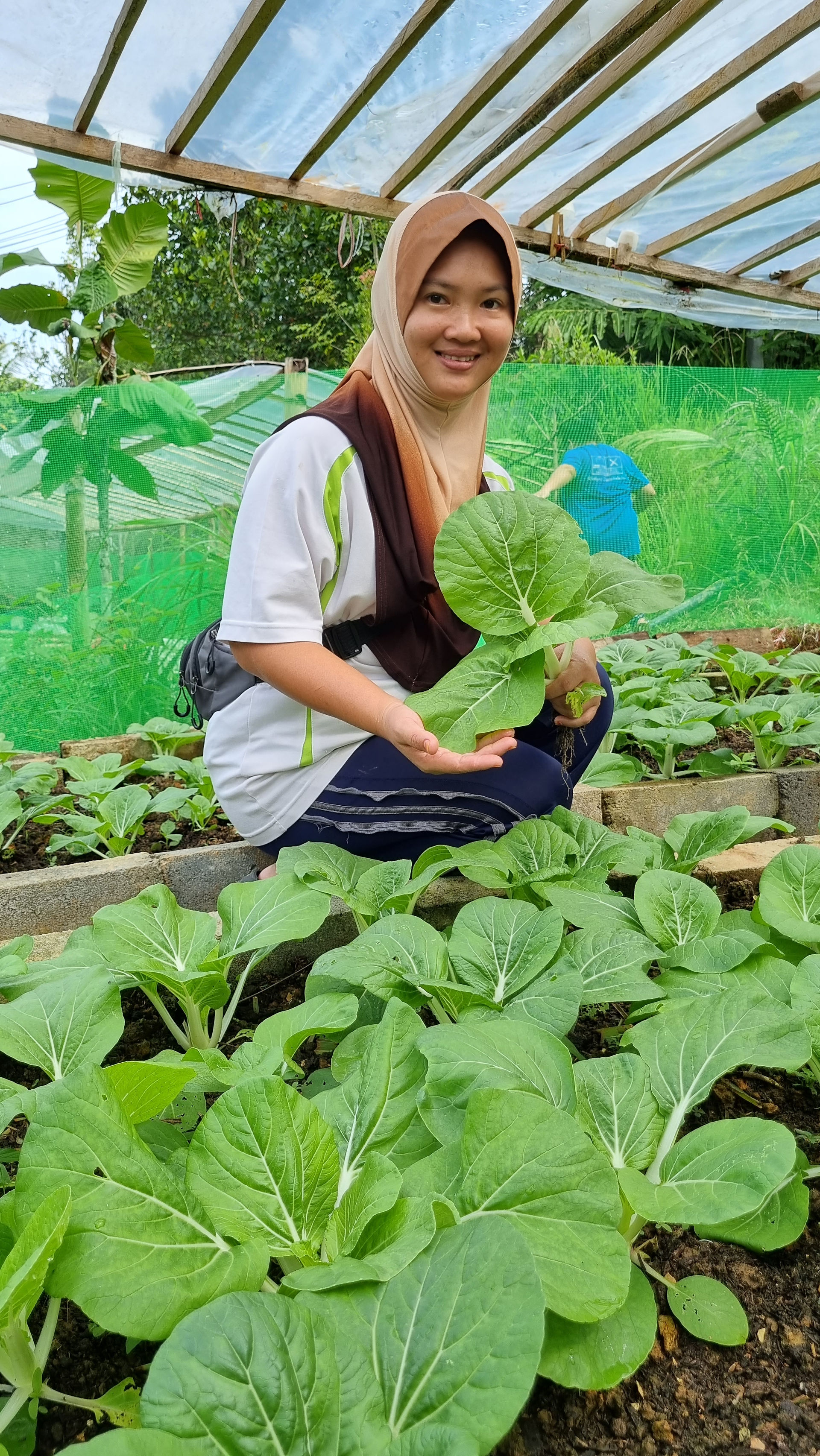 Rural farmer standing among raised garden beds filled with self-grown vegetables in her village