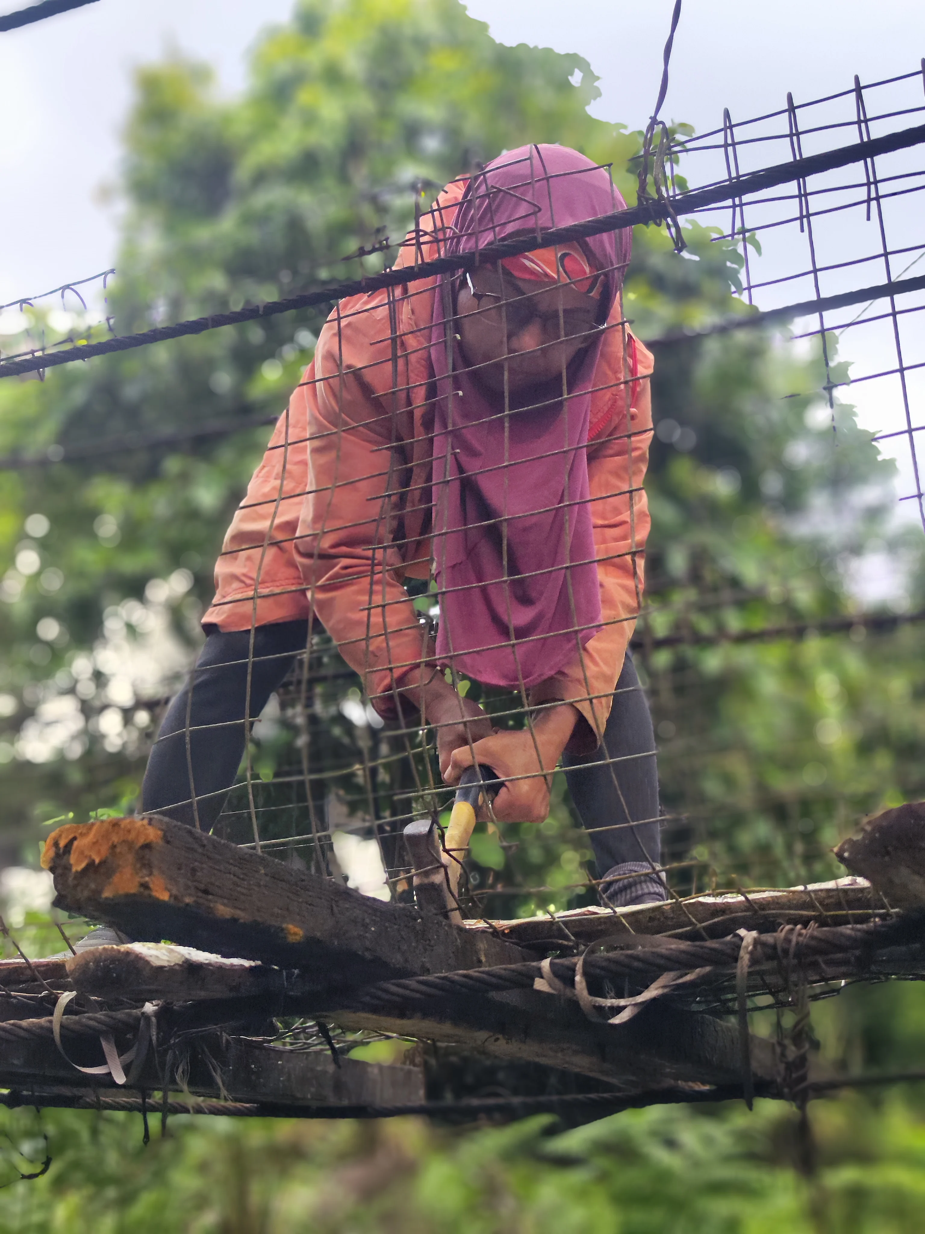 rural woman using a hammer to remove the old wooden planks from the bridge