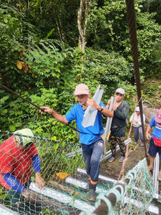Community members carrying project materials to support bridge repair efforts.