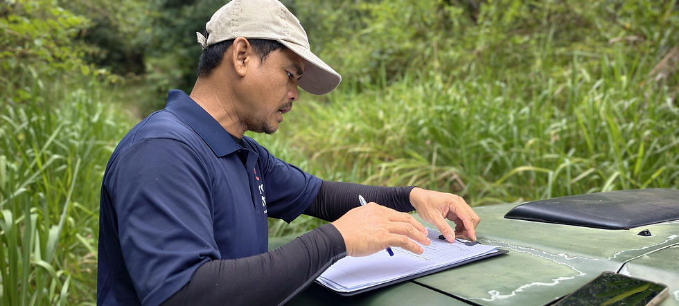RuralKita field team member reviewing handwritten assessment forms on a clipboard placed on a vehicle bonnet during a community field visit in Kampung Talukung, Kota Belud, Sabah.